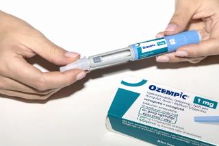 Patient holding Ozempic injection amid reports of severe gastrointestinal side effects