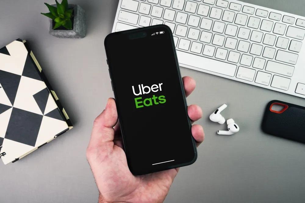 Uber Eats delivery app launching on a smartphone screen held by a gig worker