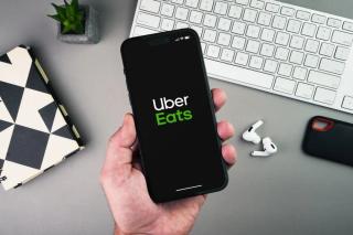 Uber Eats delivery app launching on a smartphone screen held by a gig worker