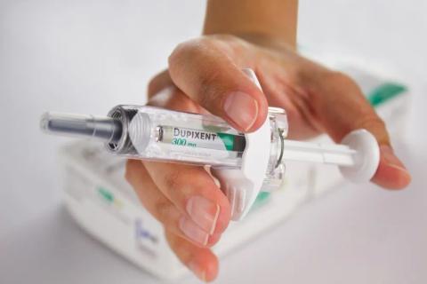 Person holding a Dupixent injection used for eczema or asthma treatment