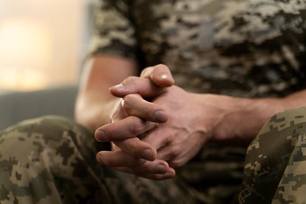 Military man sitting with hands in lap