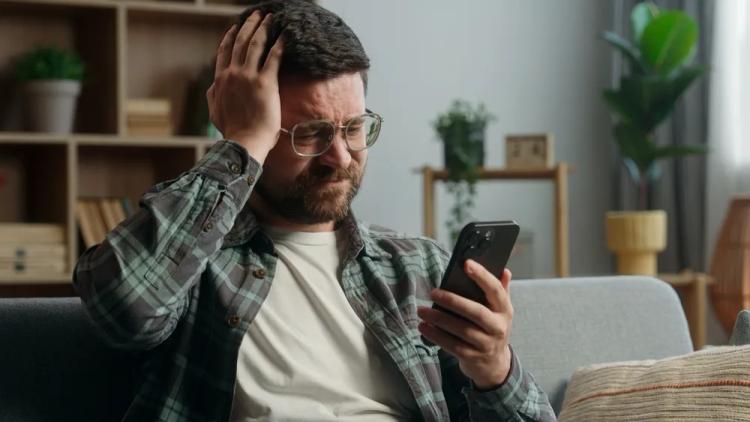 Mobile gamer holding a smartphone with visible frustration over in-game losses